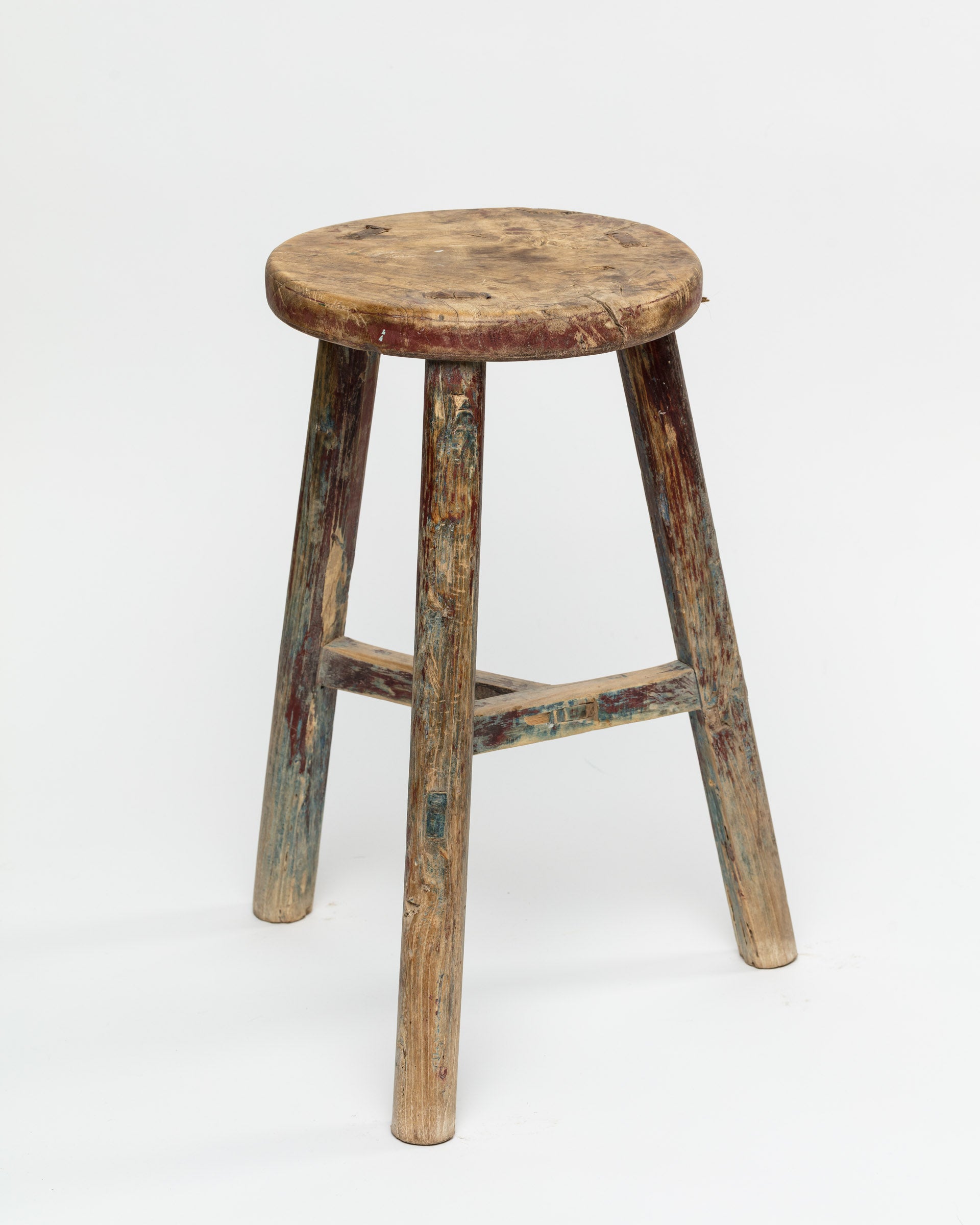 A well-worn ROUND STOOL 48 with visible paint remnants and signs of aging from a Scottsdale, Arizona bungalow, set against a white background. (Indus Design Imports)