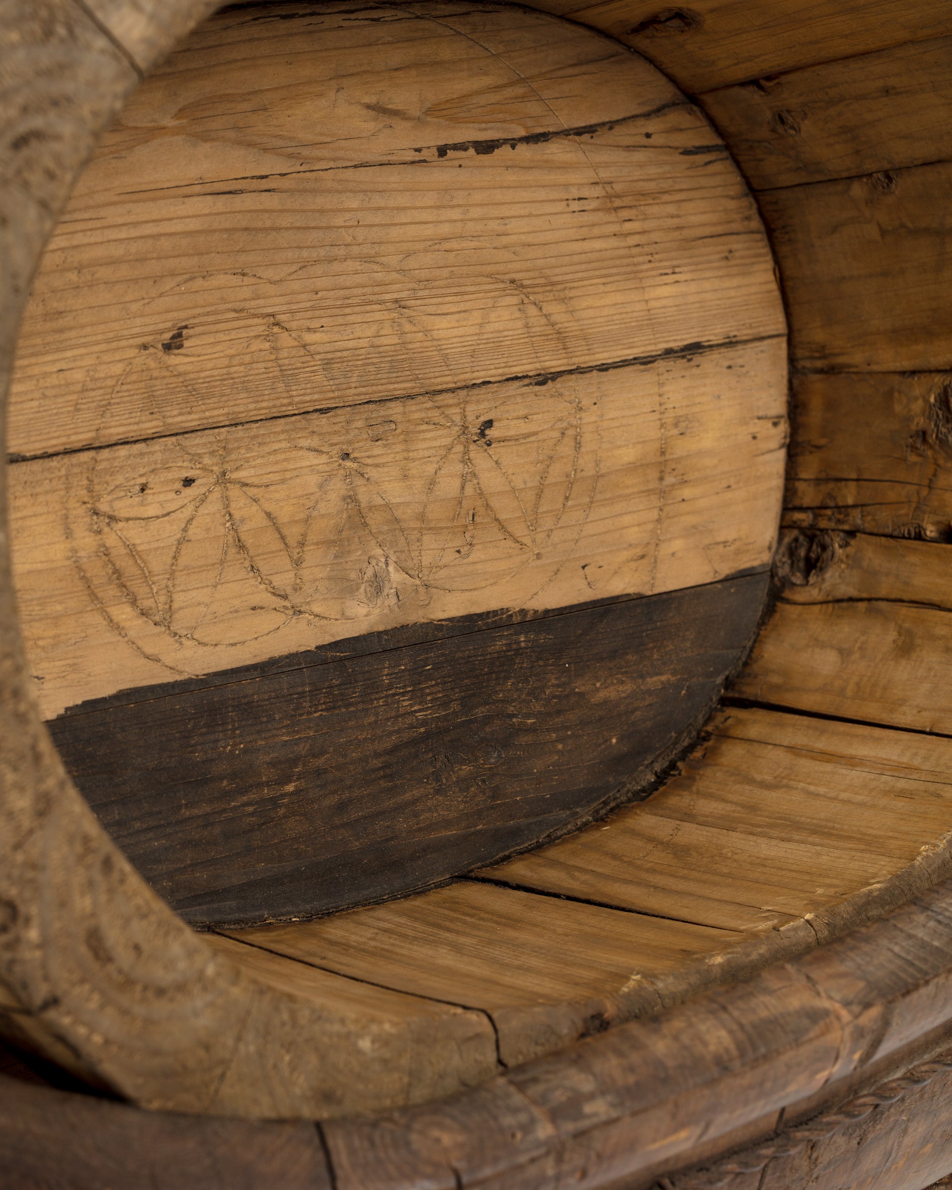 Close-up view of an Oval Wood Bucket 10 end in Scottsdale, Arizona, with hand-carved patterns, showing concentric circles and scratch marks on textured wood by Indus Design Imports.