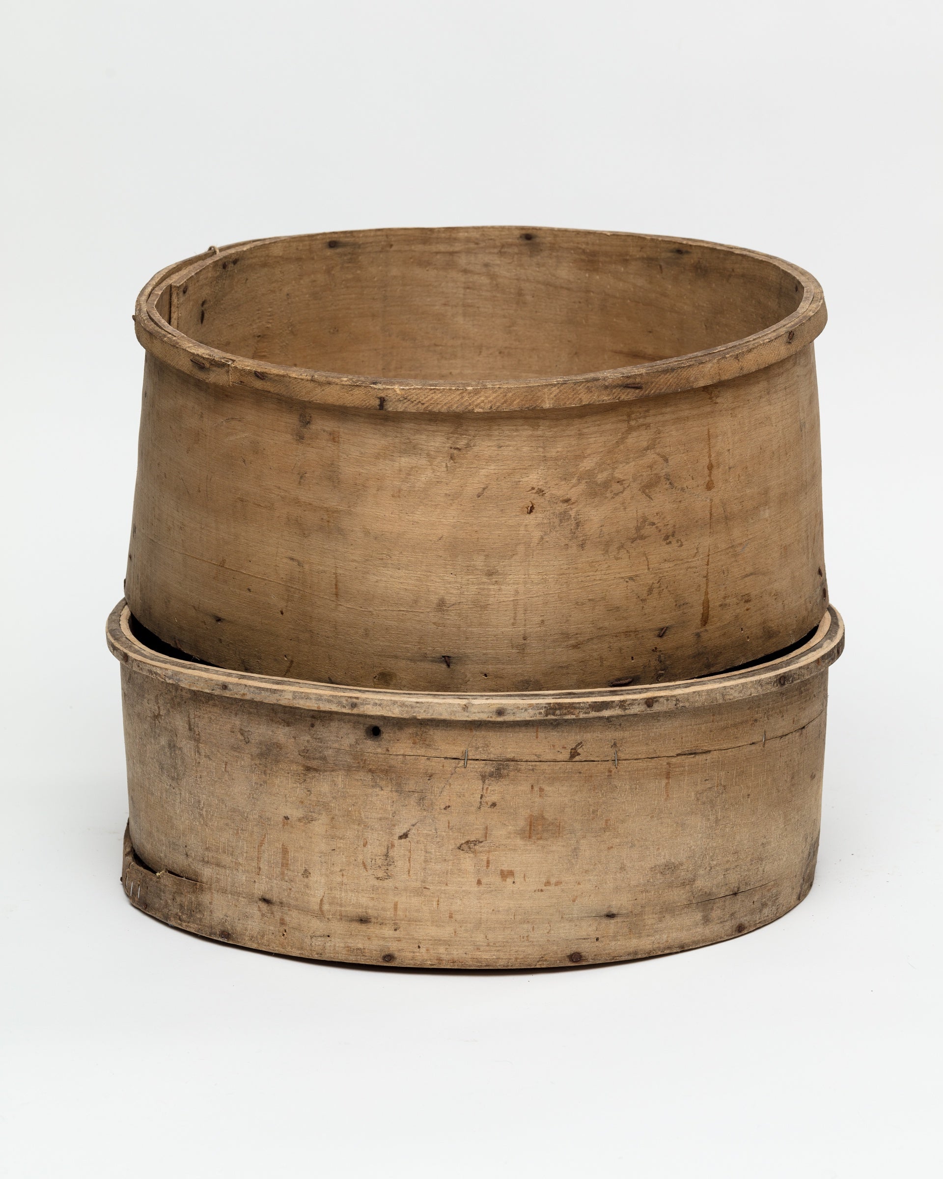 Two aged, circular wooden sieves stacked together against a plain white background, often found in a Scottsdale Arizona bungalow, showcasing faded patina and visible signs of wear and tear. This is the CHEESE MOLD BUCKET 35 from Indus Design Imports.