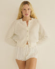 Petra Cardigan by DOEN in cream, paired with white striped shorts, styled against a light neutral background.