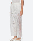 A person wearing Sea New York Gardener Pants paired with a white sleeveless top and white flat shoes.