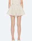 A person is shown from the back wearing Sea New York's Angelina Suiting Flare Shorts in cream with an elastic waistband, a sleeveless knit top, and cream flat shoes against a plain white background.