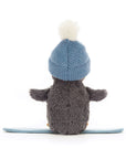 Peanut Penguin Snowboarding by Jelly Cat Inc. is a grey plush penguin wearing a blue knit hat with a white pompom, sitting on a blue snowboard, viewed from behind against a plain white background.