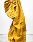 Out of Sight Poplin Jump Pant by Free City (sparrow, LLC): loose-fit yellow unisex pants with elastic cuffs and visible pockets, shown against a white background with the "freecitysupershop" logo at the bottom.