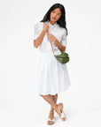Clare Vivier Petit Moyen Messenger bag styled with a white blouse and skirt, fresh minimal look against white background.