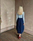 Rachel Comey Sobre Skirt in a rustic room with a woman wearing a blue top against a worn beige wall.