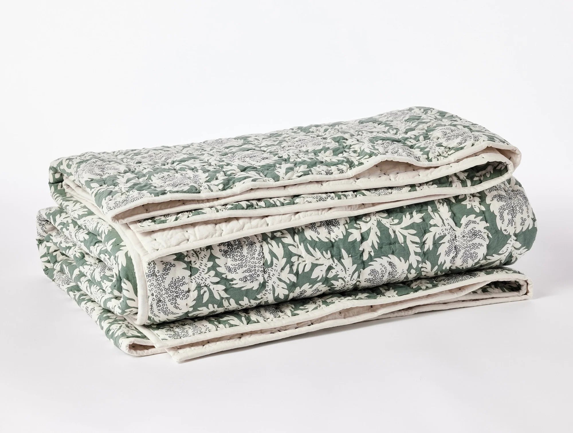 A Coyuchi Inc Robles Handstitched Org Quilt featuring a green and white floral pattern on a neutral background, perfect for a cozy bungalow in Scottsdale, Arizona. The texture appears soft and layered, highlighting the detailed stitching.