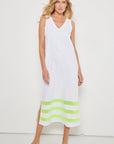 A woman models Lisa Todd's Best Dressed—a sleeveless white maxi dress with a v-neck and lime green stripes at the hem, paired with matching green flip-flops—against a plain white background.