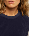 A close-up of a woman with wavy blonde hair wearing the Perfectwhitetee Saylor Loop Terry Sweatshirt, showing her lips, chin, neck, and shoulders.