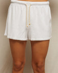 A person wears Perfectwhitetee's Summer Loop Terry Sweat Shorts—white with a beige drawstring—against a plain, light background. The photo is cropped from waist to mid-thigh.