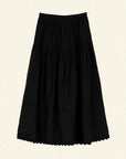 The Sebastiane Skirt by DOEN is a black, high-waisted A-line skirt in organic cotton with gathered fabric and subtle lace trim at the hem, shown against a light beige background.
