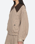 A woman stands in profile wearing the Sea New York Savannah Plaid Jacket, featuring an oversized ribbed-knit collar, large pockets, sleeve button details, and a contemporary fit with matching plaid pants.