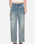 Wearing Sea New York’s Claira Mended Jeans—relaxed fit, wide-leg, high-waist, light-wash patchwork denim with visible stitching—and a sleeveless cream knit top; only the lower torso and legs are visible.