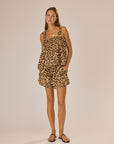 A woman stands against a plain background, wearing the flowy, artisan-made Jasmine Top in a Bali leopard print by natalie martin with matching shorts. She has long straight hair, a relaxed expression, and black sandals.