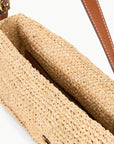 Close-up of the Staud Harlow Raffia Bag in natural, featuring an open top, brown leather-trimmed strap, and a glimpse of the interior lining.