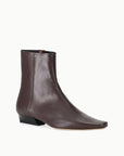 Brown leather ankle boot with pointed toe and low black heel by Staud, Wally Sock style on white background.