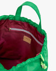 The Sac Tout by Clare Vivier features a green nylon exterior, maroon lining, zippered pocket, leather "Clare V." patch label, and both handles and a crossbody strap for versatile carrying.