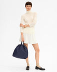Clare Vivier Sac Tout Navy tote styled with a white turtleneck and pleated skirt, Bungalow Furniture & Accessories.