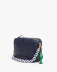 The Clare Vivier Sardine FOB is a small, rectangular navy blue woven handbag featuring a gold zipper, chunky blue-and-white checkered beaded strap, vintage gold-plated brass accents, and a green fish-shaped keychain.