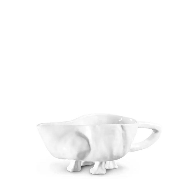 A white porcelain Gravy Boat No. 151 by Montes Doggett with a unique bungalow-inspired design that looks like a cow, featuring legs as the base and a tail-shaped handle, on a white background.