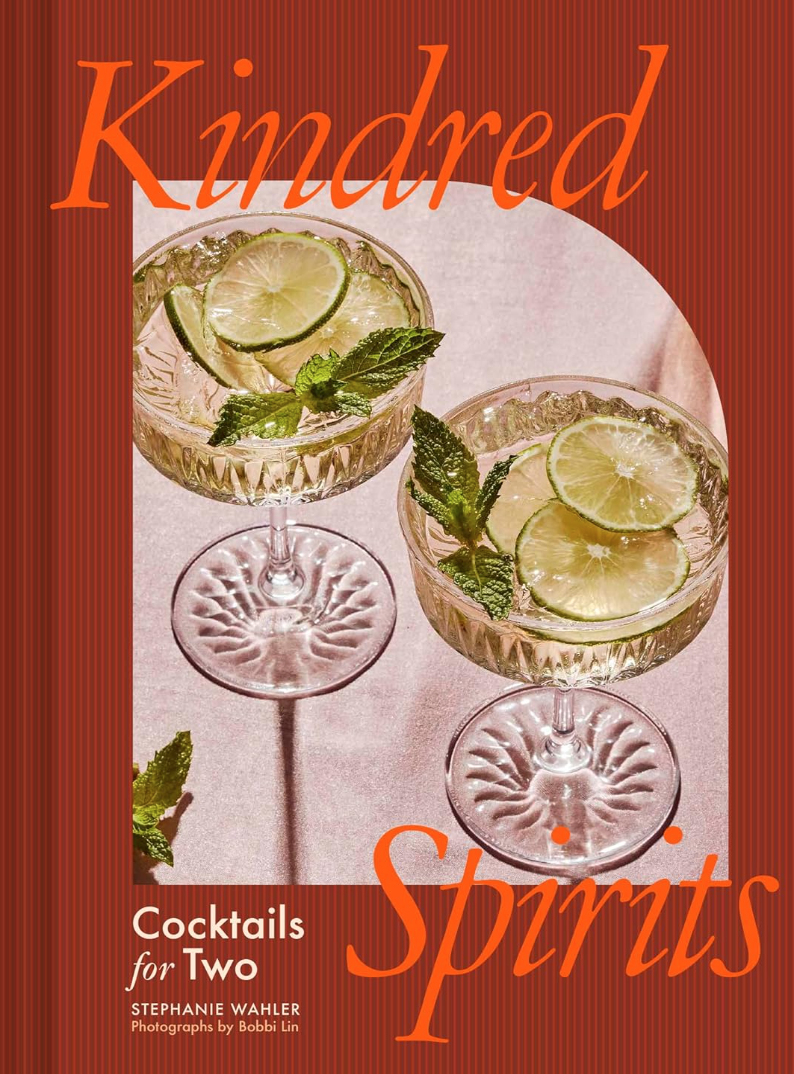 Cover of &quot;Kindred Spirits: Cocktails for Two&quot; by Hachette Book Group featuring two cocktails with lime slices and mint on a textured pink surface, photographed at a Scottsdale, Arizona bungalow, with the subtitle &quot;Cocktails for Two&quot; by Stephanie Wahler.