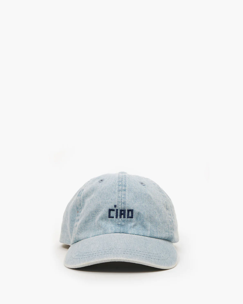 A light blue Clare Vivier denim baseball cap with the word &quot;CIAO&quot; embroidered in black on the front, centered over a white background and designed in Arizona style.