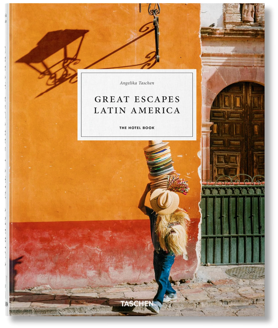 A book cover published by Ingram Book Company titled "Great Escapes Latin America" featuring a person in a straw hat, balancing a stack of colorful woven baskets on their head, standing by a vibrant orange bungalow.