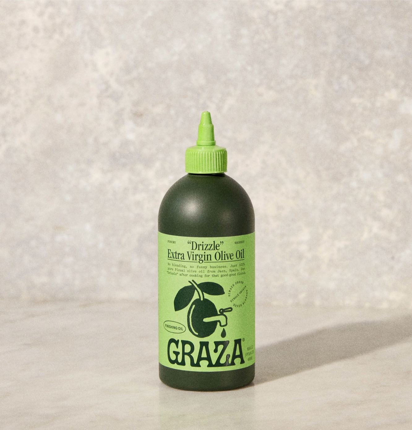 A bottle of Faire "Drizzle" extra virgin olive oil, featuring a dark matte bottle with a green cap, set against a textured gray background, ideal as a finishing oil.