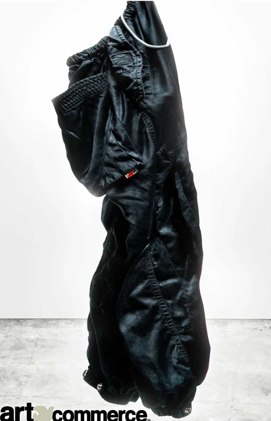 A puffy black winter coat stands upright on its own, seemingly filled with air. The coat's textural details and a small red tag marked "MADE IN USA" are visible against a white background.