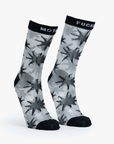 The Step Up Sock by Mother is designed with a translucent grey fabric adorned with bold black star patterns. They feature black tops, each displaying the words "MOT" and "FUCK" in white text. The heel and toe areas are stylishly accentuated in black.