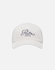 The FRAME Ritz Cotton Trucker is a 100% cotton cap with the Ritz Paris logo embroidered in black script on a plain white background.