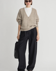 Apiece Apart Softest Silk Cashmere V-Neck Marl sweater styled with wide black pants and a black handbag.