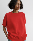 Red Rachel Comey Billi Sweatshirt paired with light blue jeans, modeled against a plain backdrop.