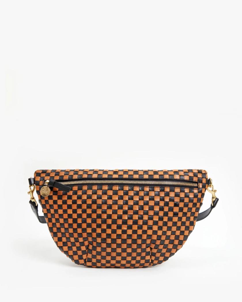 A small, stylish Clare Vivier Grande Fanny Woven Checker with a checkered pattern in black and orange. The bag features a gold zipper and a black strap, evoking the hues of an Arizona sunset, displayed against a white background.
