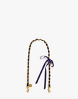A stylish camera strap featuring the Grosgrain in Chain Shoulder Strap Navy/Red Grosgrain Chain by Clare Vivier, with a navy and yellow braided design with gold-tone hardware and a small blue bow tied near one end, displayed against a plain white Bungalow background.