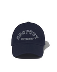 A navy blue, 100% cotton baseball cap with the words "DROPOUT UNIVERSITY" embroidered in white letters on the front. Featuring an adjustable closure, the Kule THE DROPOUT KAP NAVY casts a shadow on a white background.