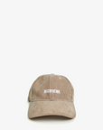 A beige Clare Vivier baseball hat with the word "DISCOTHEQUE" embroidered in a lowercase serif font on the front. The Baseball Hat Stone Corduroy Discothèque, reflecting an Arizona style, is displayed against a plain white background.