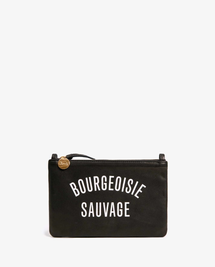A black rectangular wallet clutch with tabs from Clare Vivier, featuring the words &quot;BOURGEOISIE SAUVAGE&quot; printed in white block letters on the side and a gold zipper pull against a white background, exemplifies Arizona style.