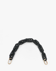 A short, thick black resin chain strap with gold metal clasps at both ends, arranged in an arch shape against a white background. This stylish Clare Vivier Shortie Strap easily attaches to any bag for a sleek finish.