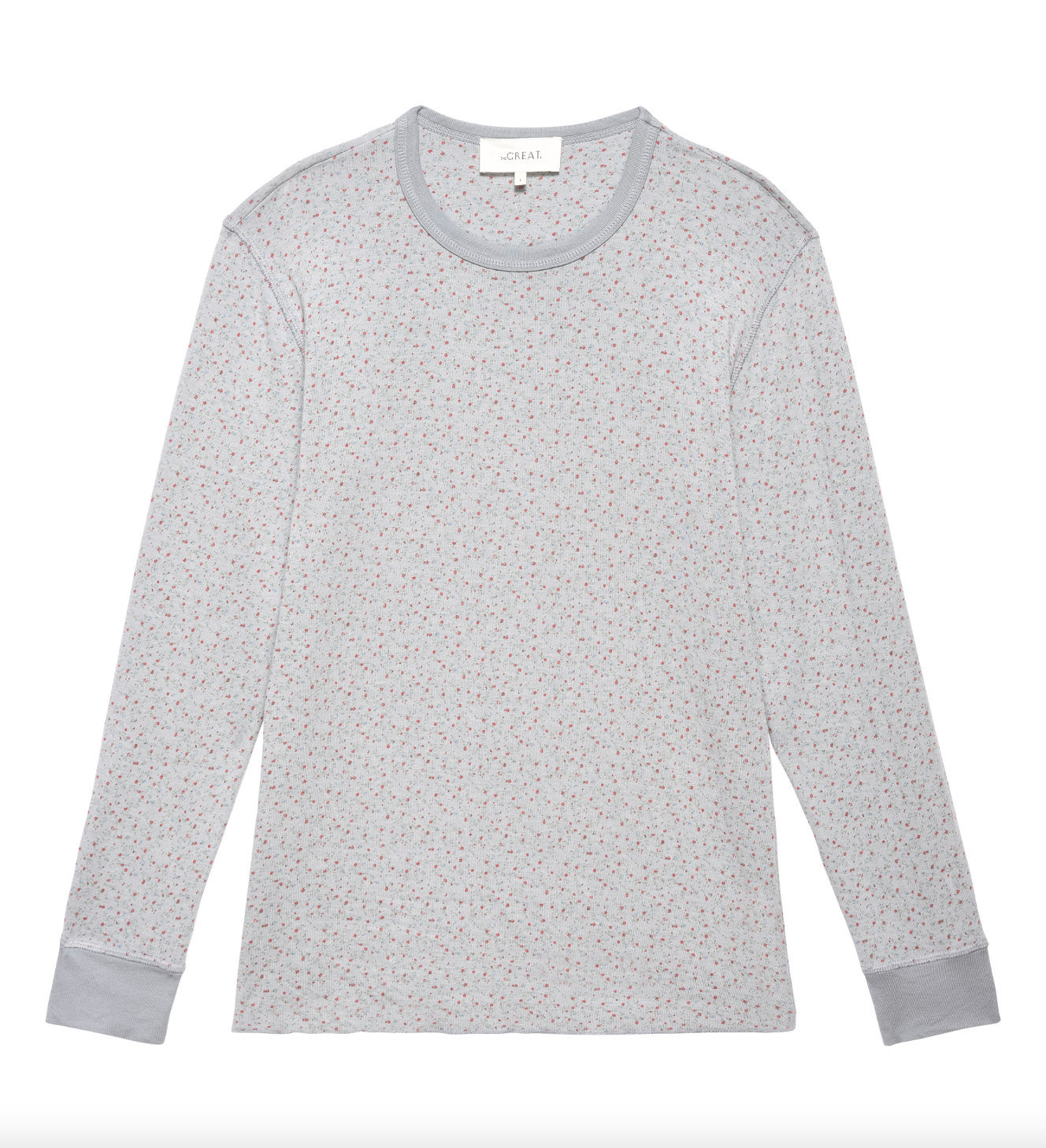 A light gray long-sleeve shirt with a subtle speckled pattern featuring small, multicolored dots. The collar and cuffs are slightly darker gray, reminiscent of a cozy Scottsdale bungalow. A label is visible at the inside back of the collar. Introducing THE SURPLUS CREW BLUEBELL GREENHOUSE FLORAL by The Great Inc.