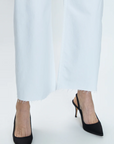 A close-up view of a person wearing the Pistola PENNY HIGH RISE WIDE LEG CROP - BLIZZARD trousers with classic black pointed-toe heels against a light grey background, embodying Los Angeles-based style.