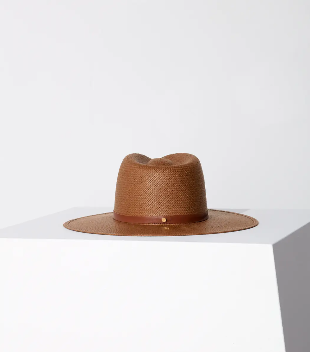 A Janessa Leone SHERMAN HAT BROWN rests on a white cube against a two-tone gray and white background, emphasizing its distinct Arizona style and texture.