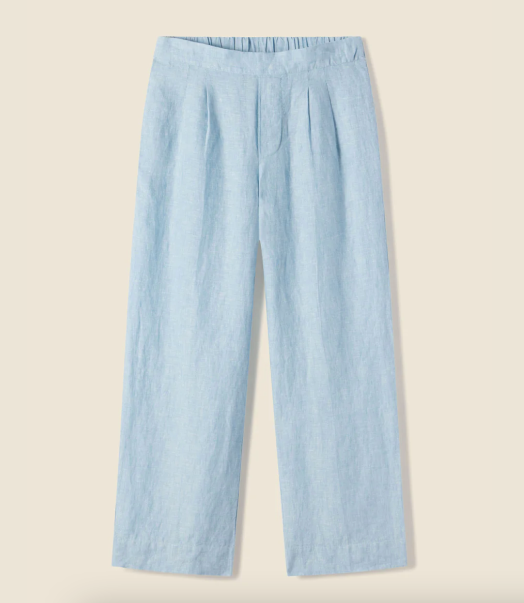 Sentence with replacement: The Trovata LEIGH PANT SKY LINEN displayed against a plain, light beige background. The pants feature a high waist, elastic waistband, and Arizona style.
