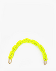 A bright yellow resin chain strap with brass spring links and gold-tone clasps at both ends, creating a curved shape against a plain white background, attaches to any bag. The Shortie Strap by Clare Vivier adds a vibrant touch to your accessories.