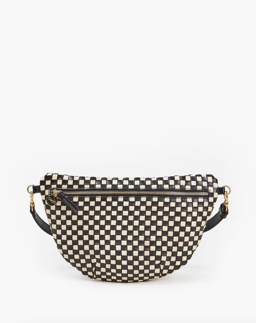 A stylish Grande Fanny Woven Checker fanny pack from Clare Vivier, featuring a black and beige checkered pattern, two exterior zippered compartments, mounted on a solid white background in Arizona style.