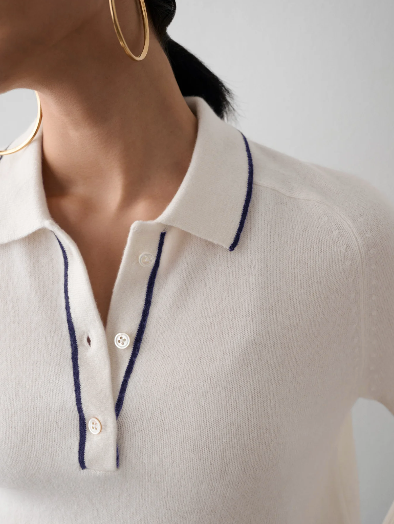 Close-up of a woman in a White + Warren Cashmere Ribbed Trim Polo with a blue-trimmed collar and a buttoned placket, wearing large hoop earrings. Only her lower face and neck are visible in Scottsdale, Arizona.