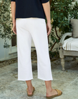 A person standing in a garden in Scottsdale, Arizona, wearing white CATHERINE Favorite Sweatpant TRIPLE FLEECE capri pants by Frank & Eileen and a dark blue top, viewed from the back. The person is also wearing tan flat shoes.
