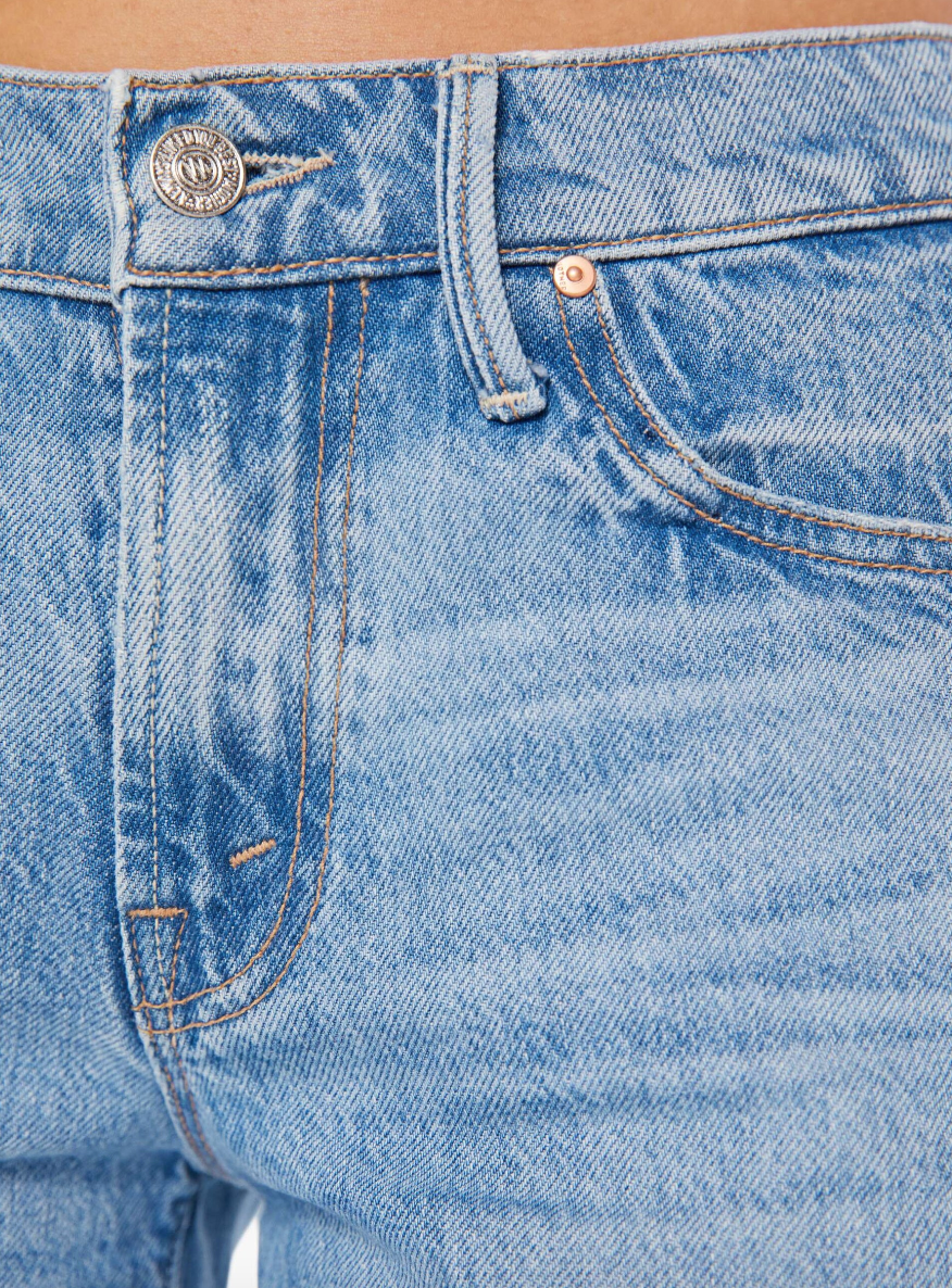 Close-up of a person wearing The Down Low Undercover Short Fray Wash denim jeans in Scottsdale, Arizona, focusing on the details like the front pocket, stitching, and buttons by Mother.