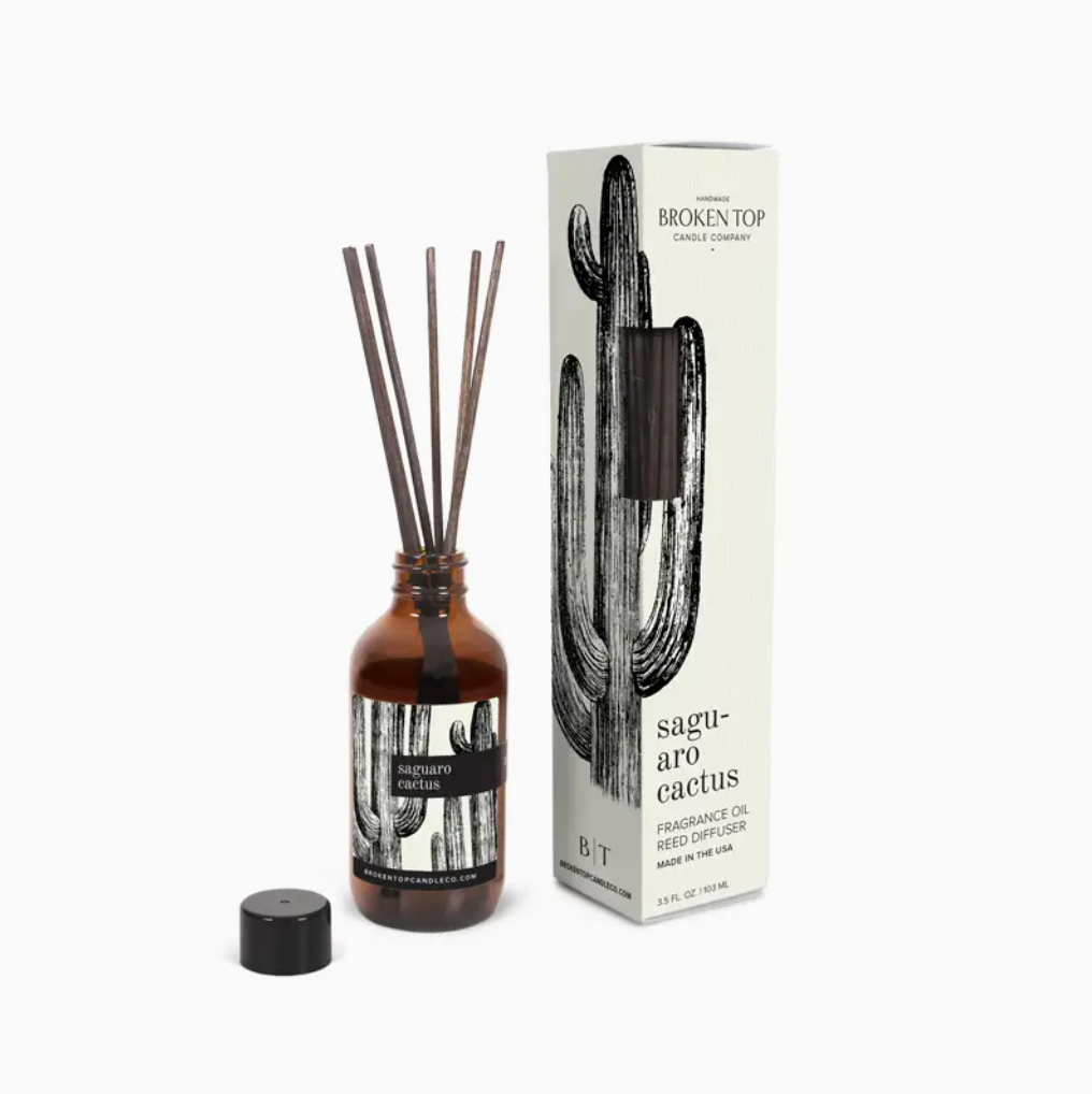 A Faire reed diffuser with a citrus scent in a small brown glass bottle with multiple reeds inserted, next to its packaging labeled "Broken Top Candle Co., SAGUARO CACTUS, Reed Diffuser.