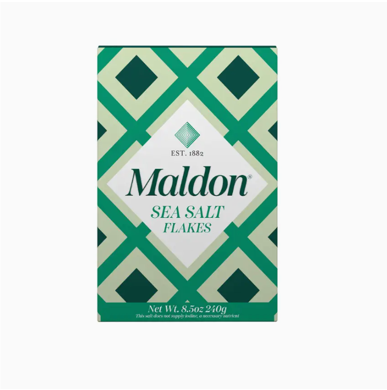 A box of Faire&#39;s Flaky Maldon Sea Salt White 8.5oz, featuring a white and green geometric pattern, with the product name prominently displayed in the center. The packaging notes a net weight of 8.5 ounces (240g) and highlights its distinct salt flavor.